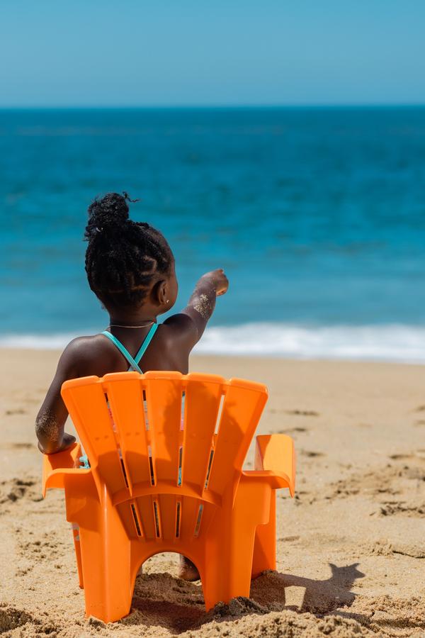 Kid in an orange chair facing the sea